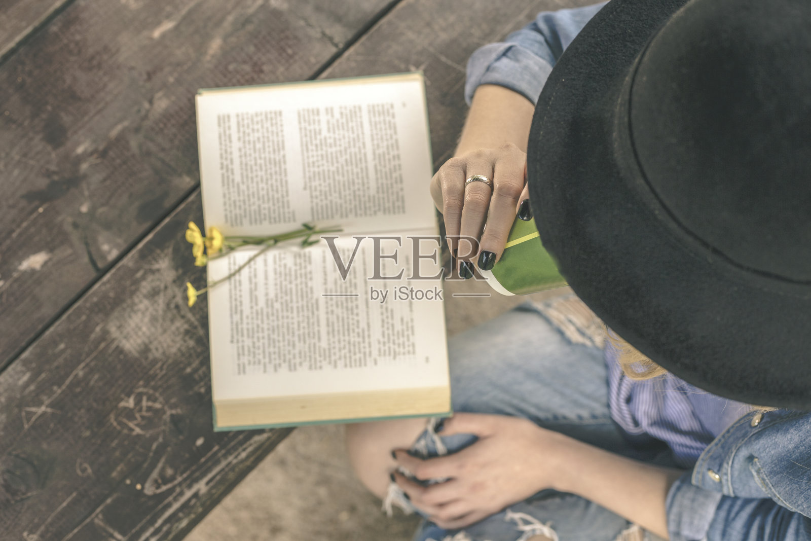 一个女人坐在公园里,手里拿着书和咖啡照片摄影图片