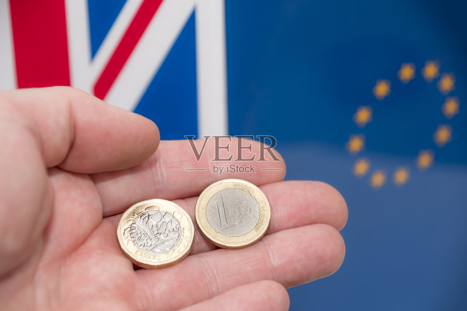 手持新的英国1英镑硬币和英国国旗照片摄影图片