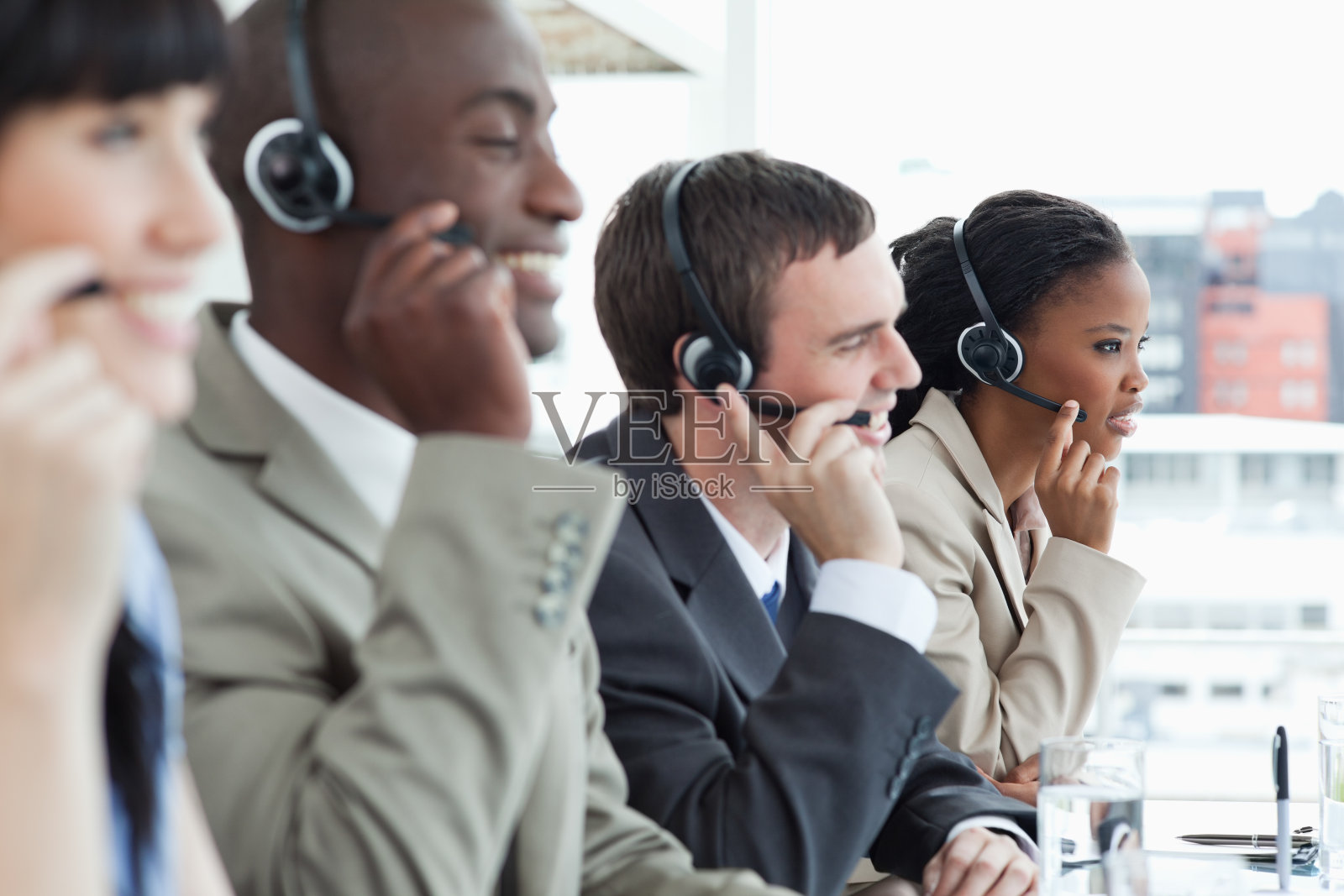 微笑的商业团队与他们的耳机在一个集中工作照片摄影图片