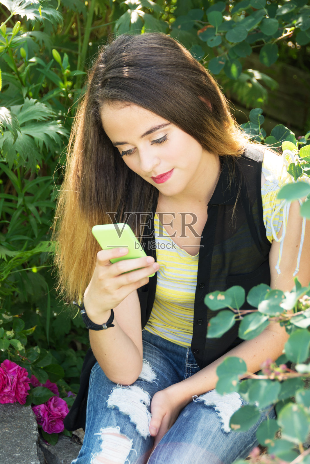 十几岁的女孩在花园里看手机,头顶的视图。照片摄影图片