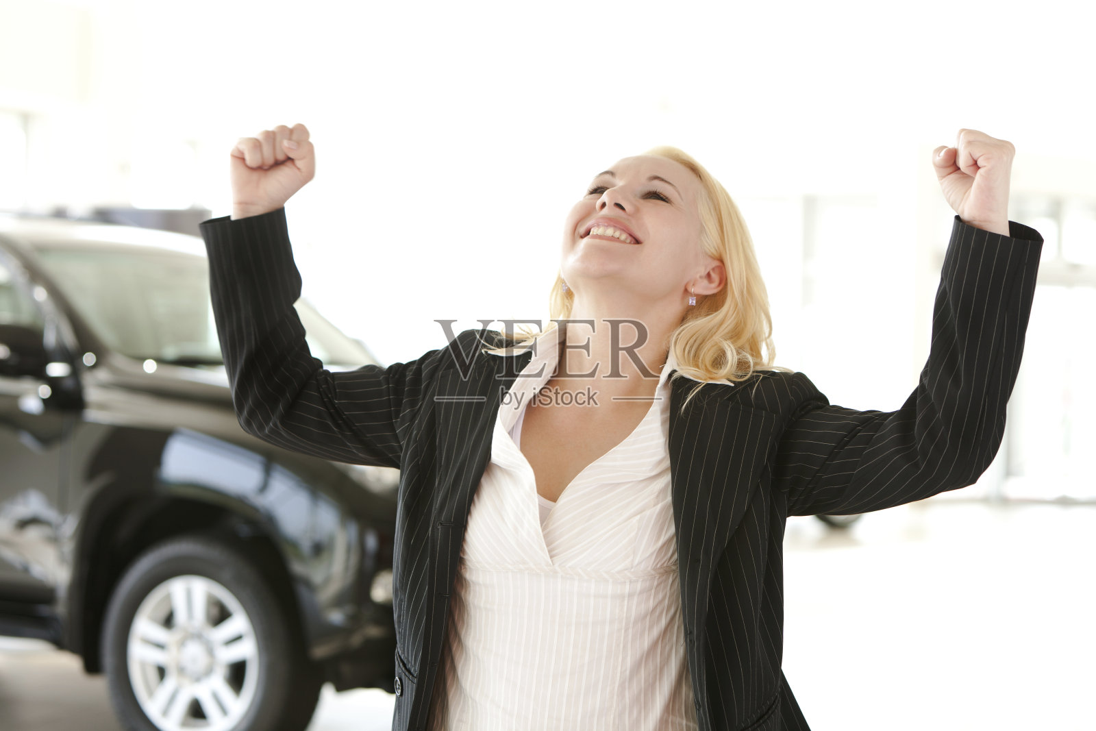 快乐和兴奋的女商人在汽车展厅举起双手照片摄影图片