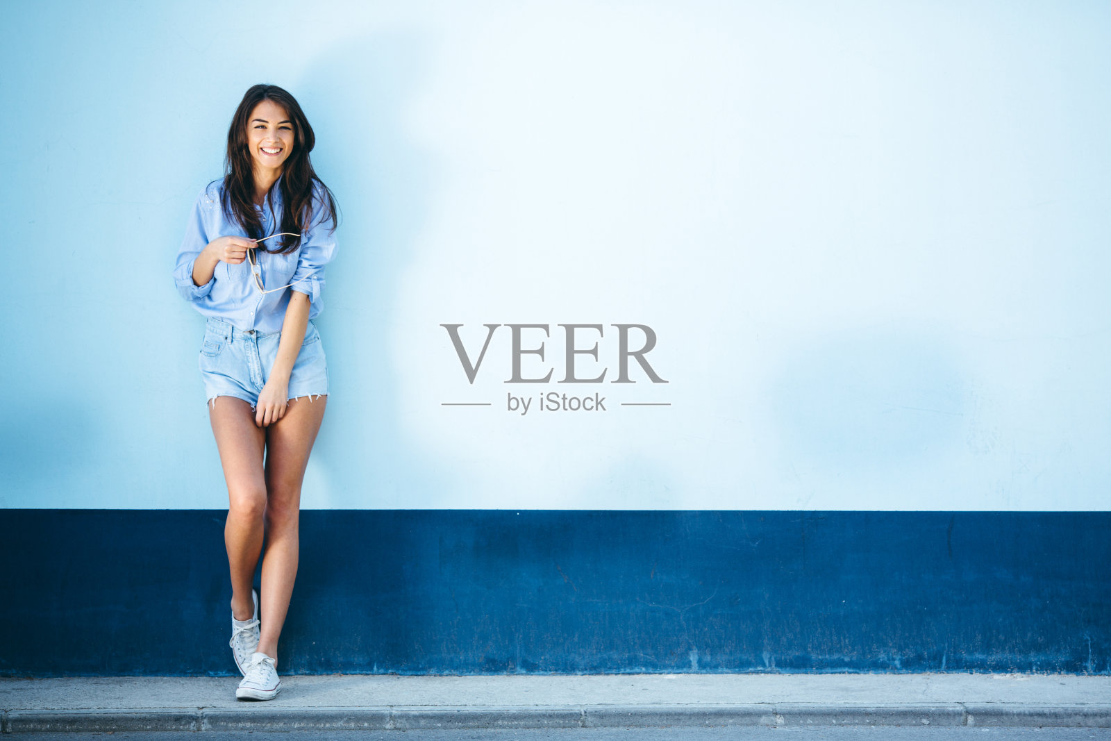 年轻女人靠墙站立照片摄影图片