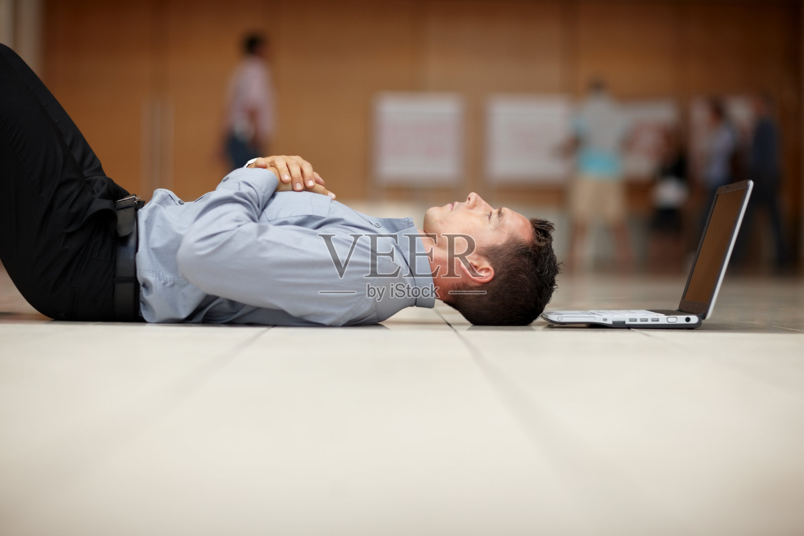 疲惫的年轻人躺在地板上拿着笔记本电脑照片摄影图片