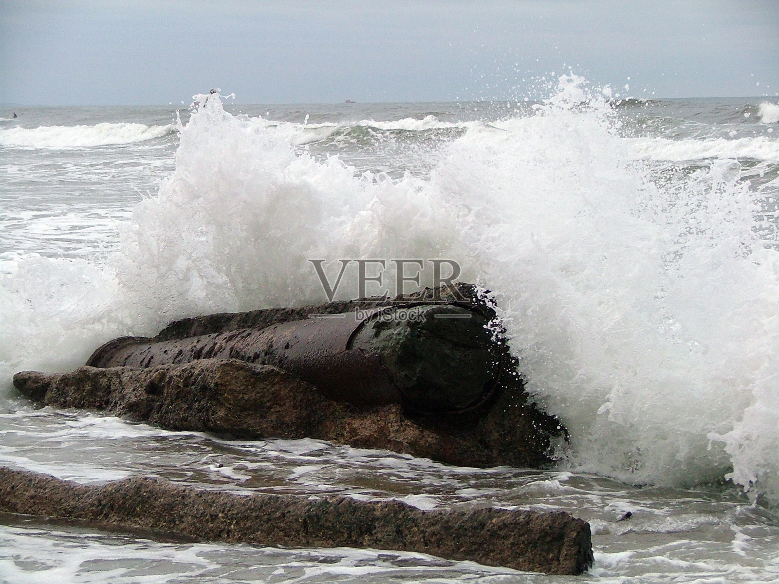 旧的和破碎的海防屏障与海浪的冲击。照片摄影图片