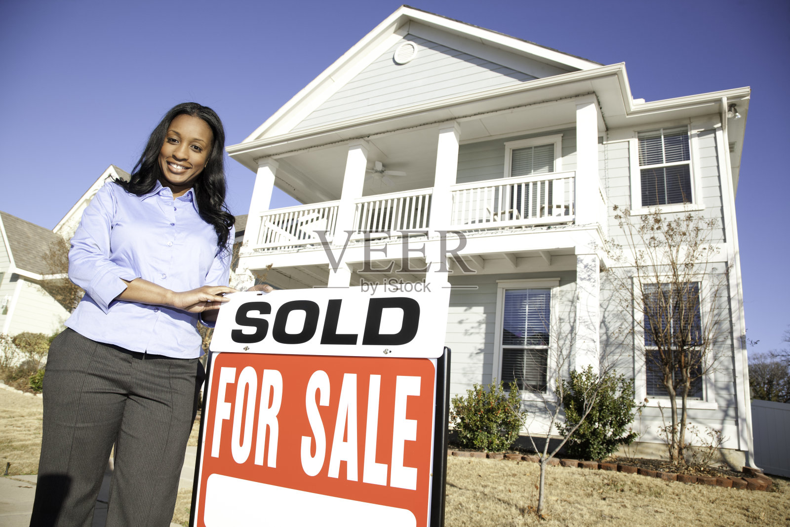 漂亮房子外面挂着卖出的标志,快乐的房地产经纪人照片摄影图片