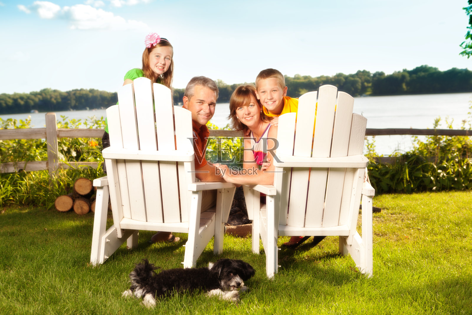 一家人和狗狗坐在明尼苏达州湖边的阿迪朗达克椅子上照片摄影图片