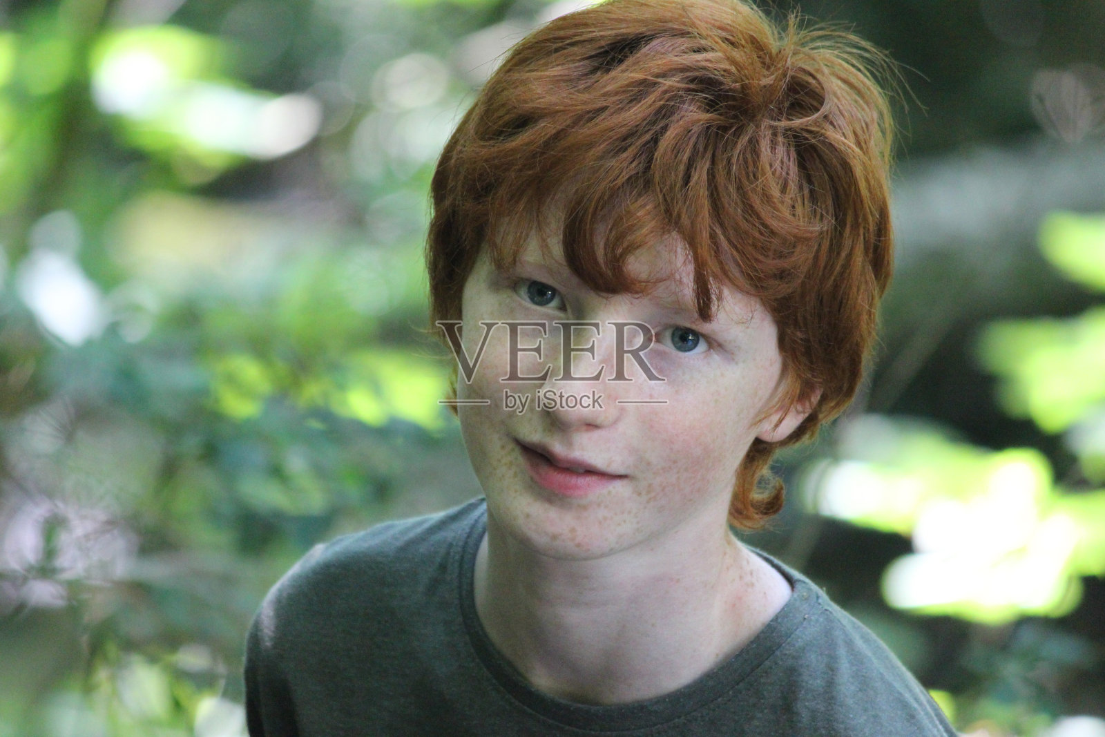 一个红发少年站在树林里的照片照片摄影图片
