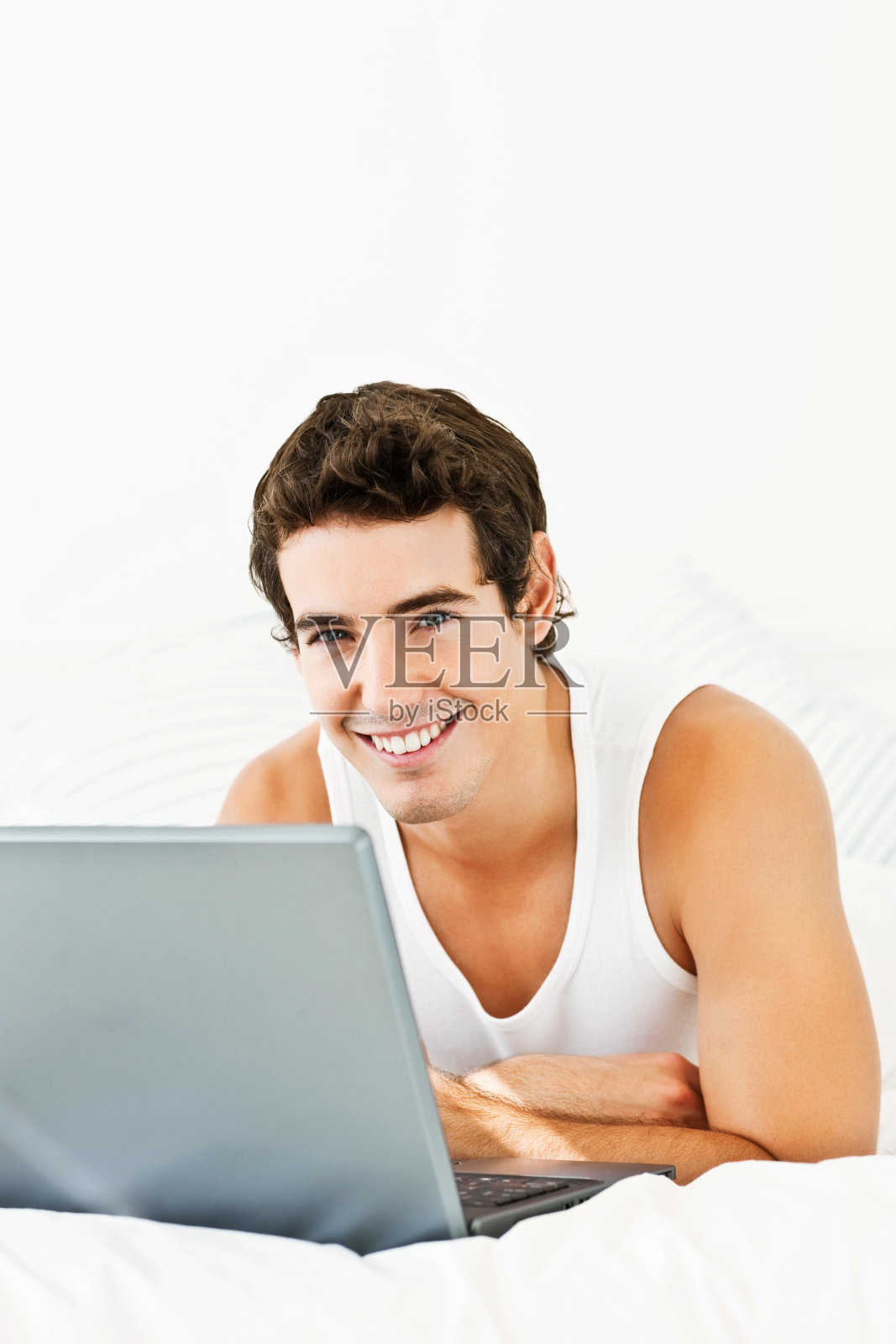 聪明的年轻人在笔记本电脑上工作,在床上休息照片摄影图片