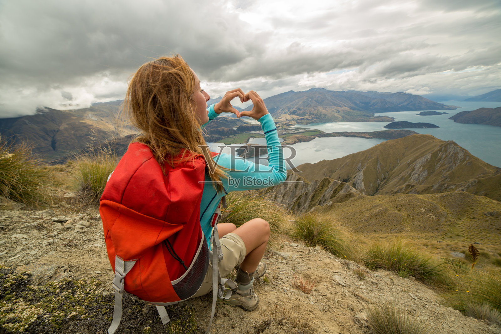 女人用手指在山湖景观前比心照片摄影图片