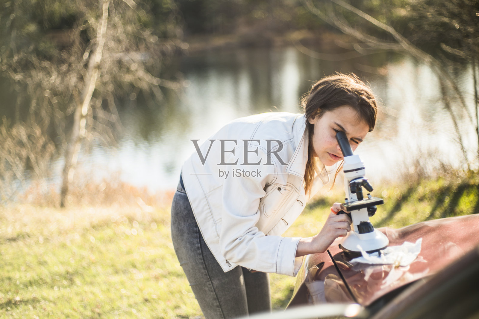 十几岁的女孩用显微镜做户外科学项目照片摄影图片
