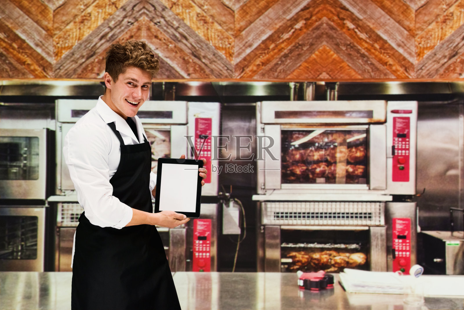微笑的厨师在厨房拿着平板电脑照片摄影图片
