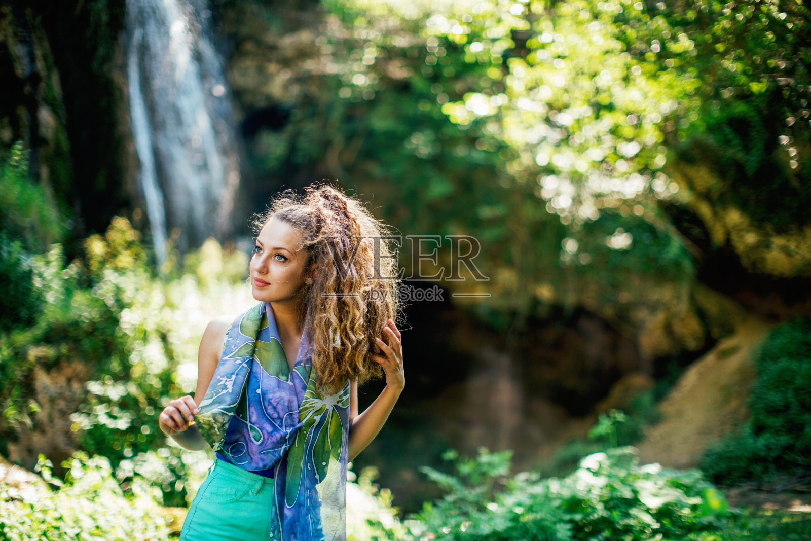 瀑布边一个漂亮的卷发女孩照片摄影图片