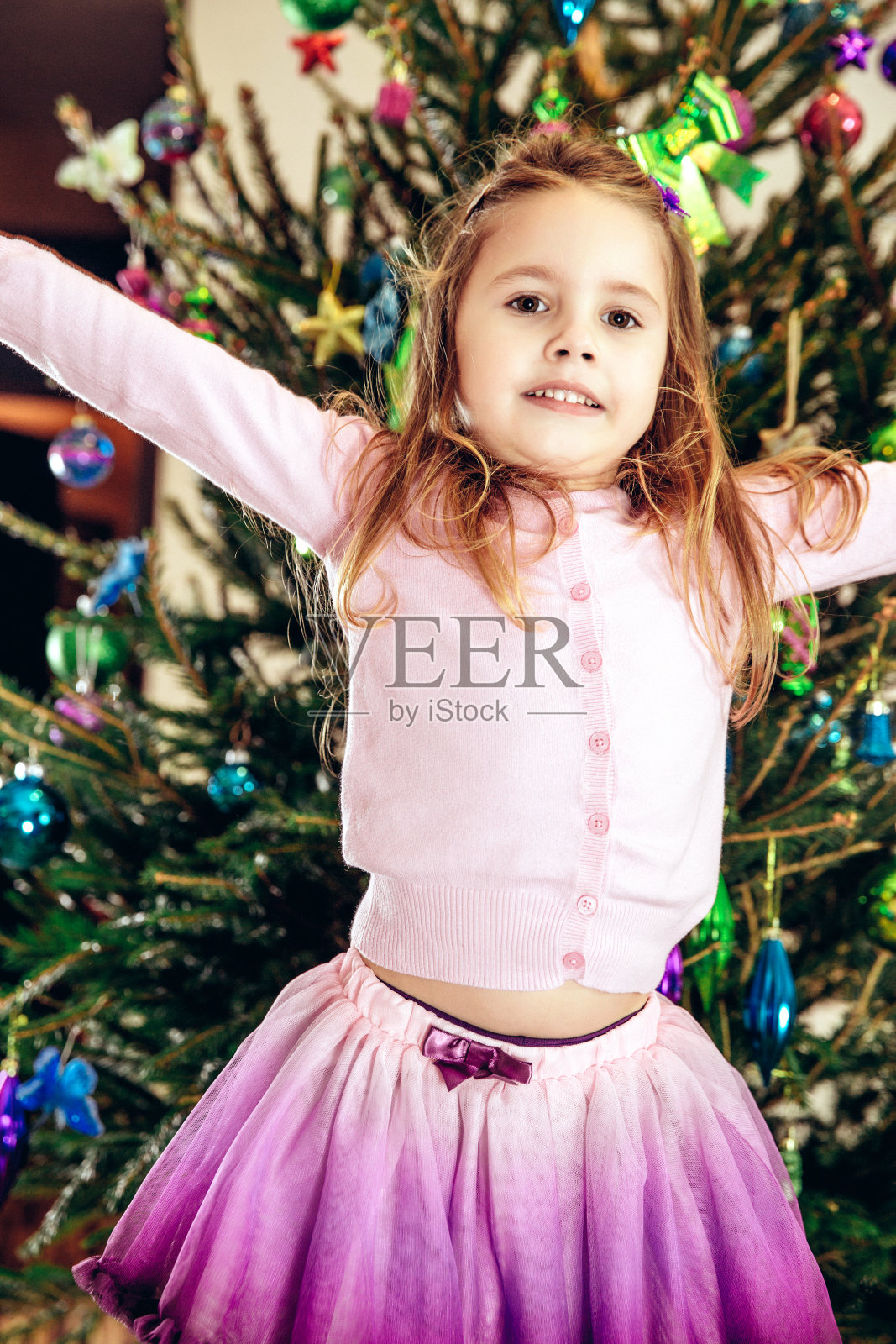 快乐的小女孩对着装饰好的圣诞树照片摄影图片