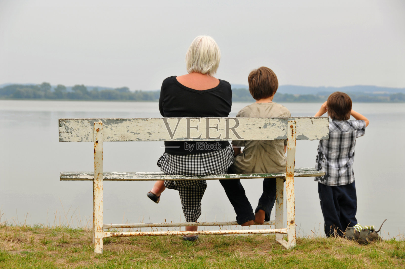 奶奶和孙子们坐在海边的长椅上照片摄影图片