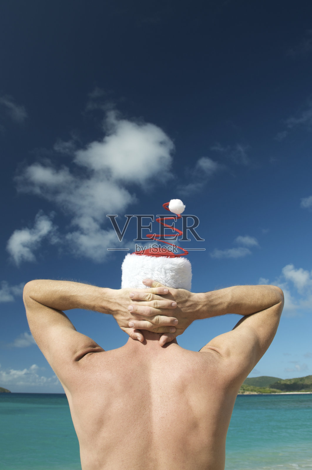 戴圣诞帽的男人看着热带景象照片摄影图片