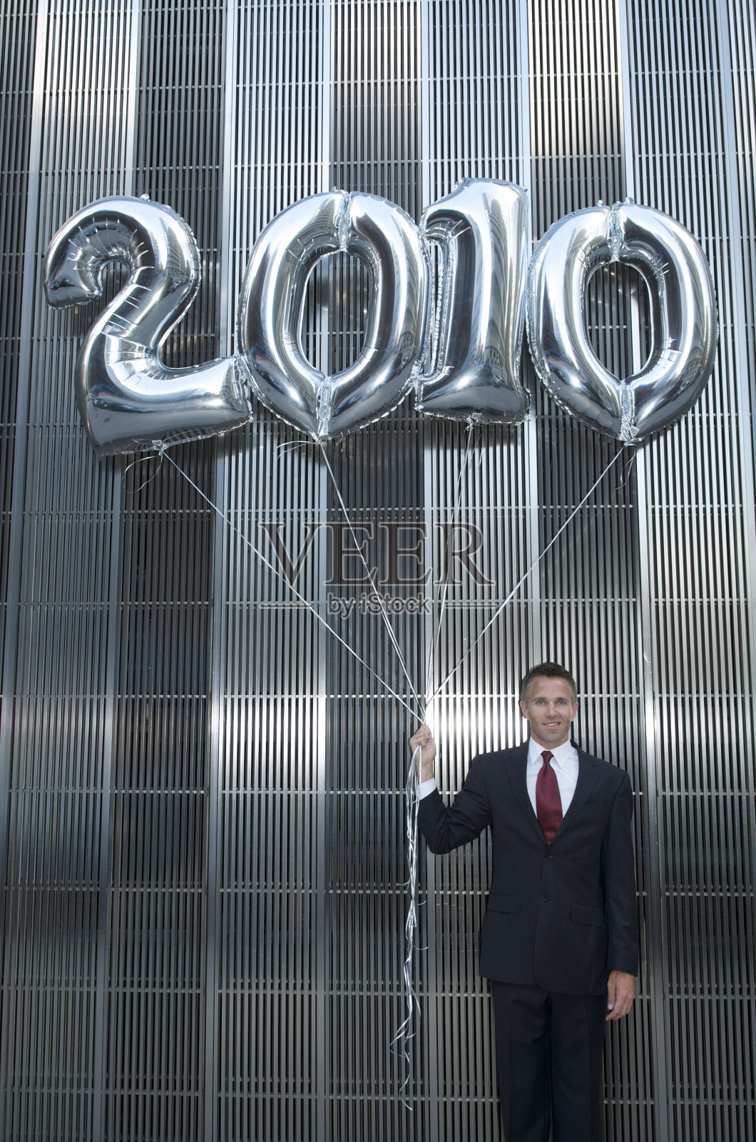 商人站在2010年闪亮的银色气球上照片摄影图片