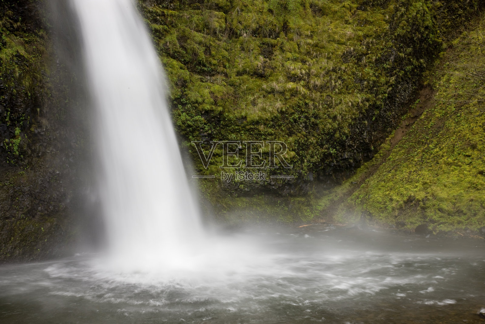 瀑布冲入被悬崖和茂密的树叶包围的水池中照片摄影图片