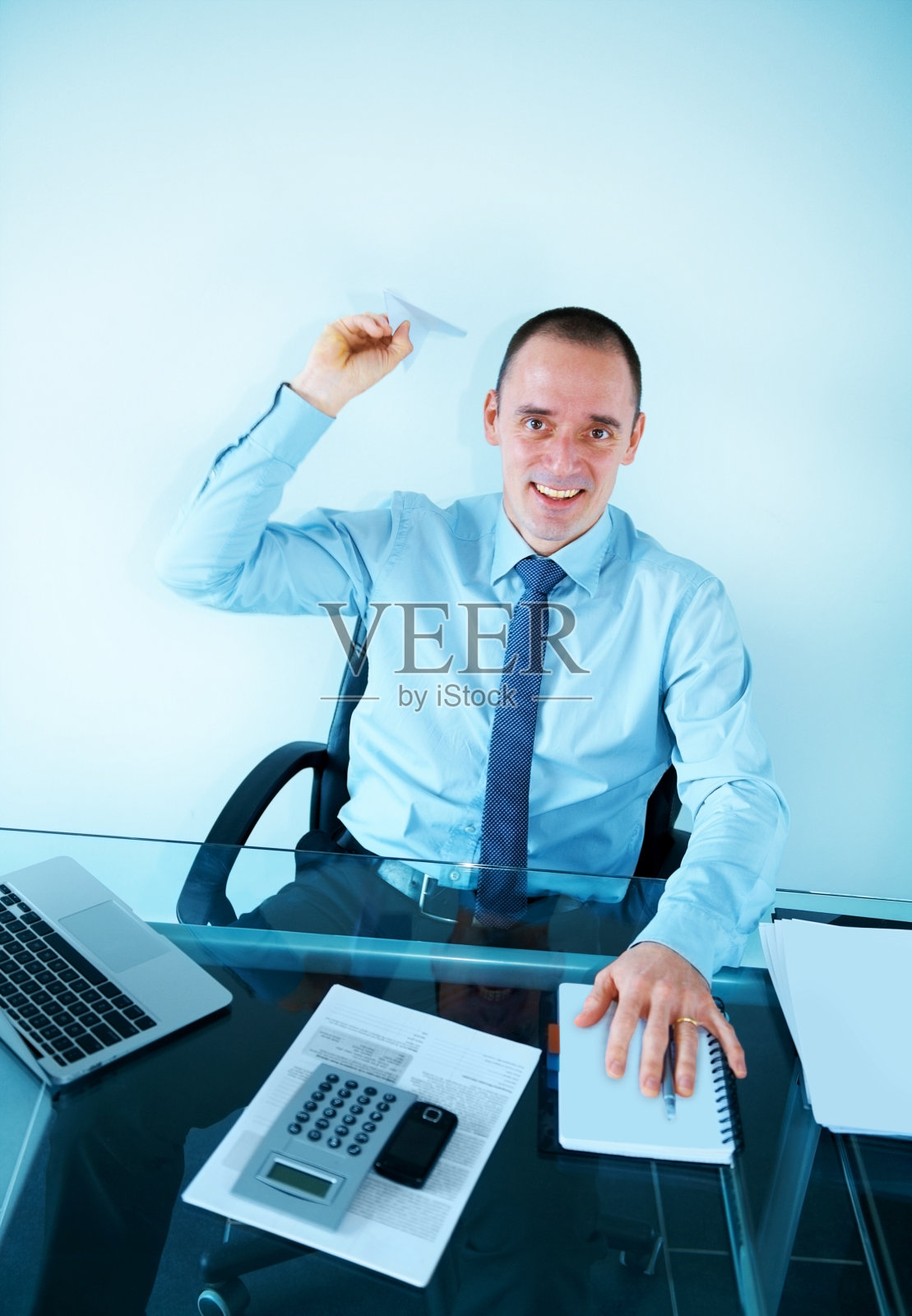 一个坐在办公室里扔纸飞机的商人照片摄影图片