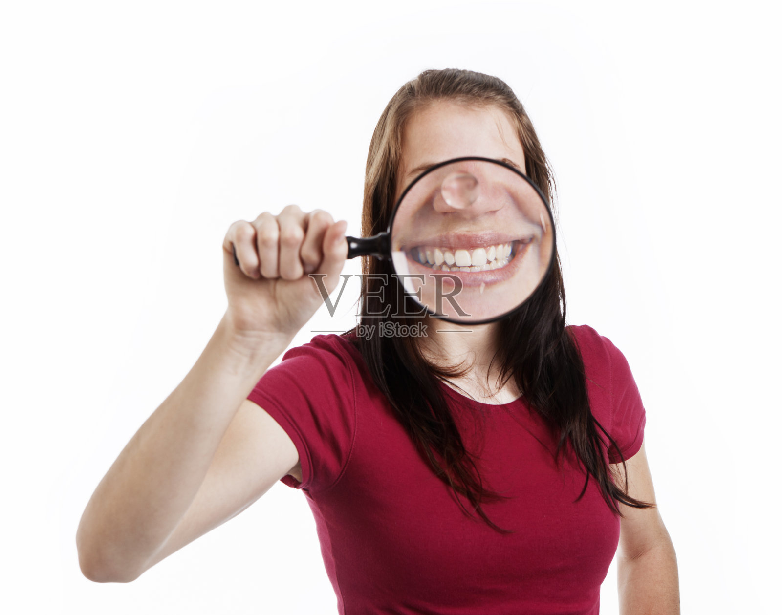 漂亮的黑发女人透过放大镜微笑——多么大的牙齿啊!照片摄影图片