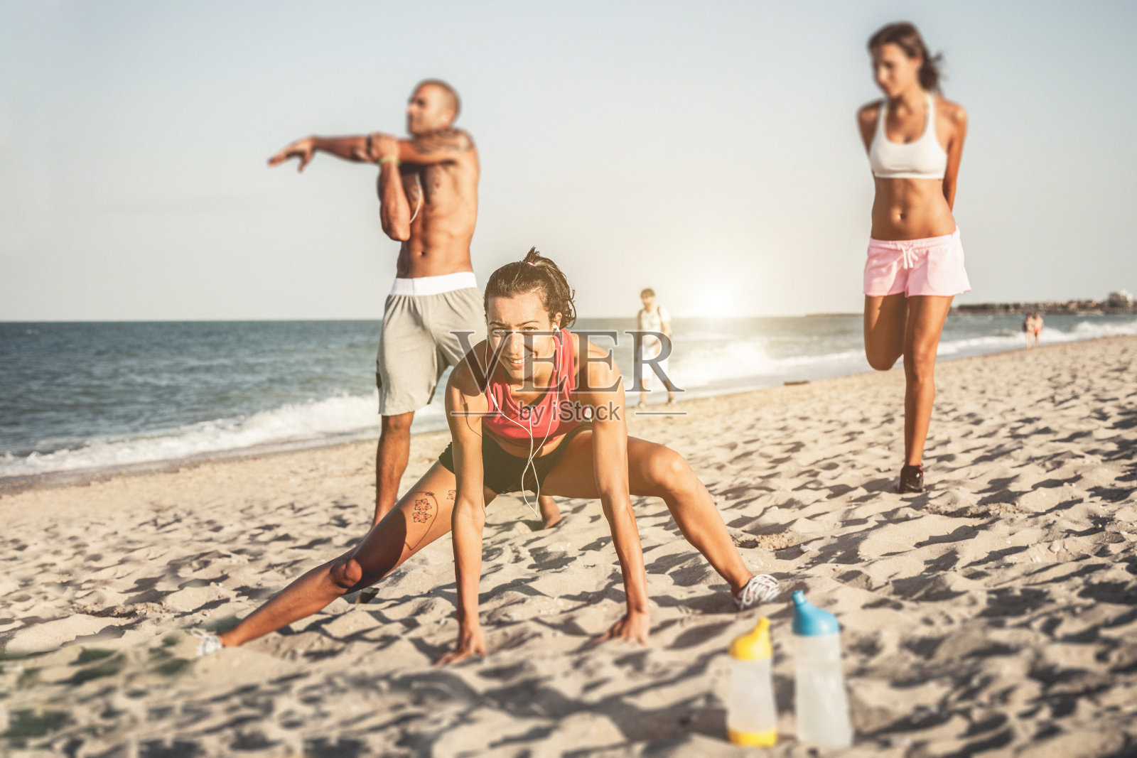 三个运动健将在海滩上放松身体照片摄影图片
