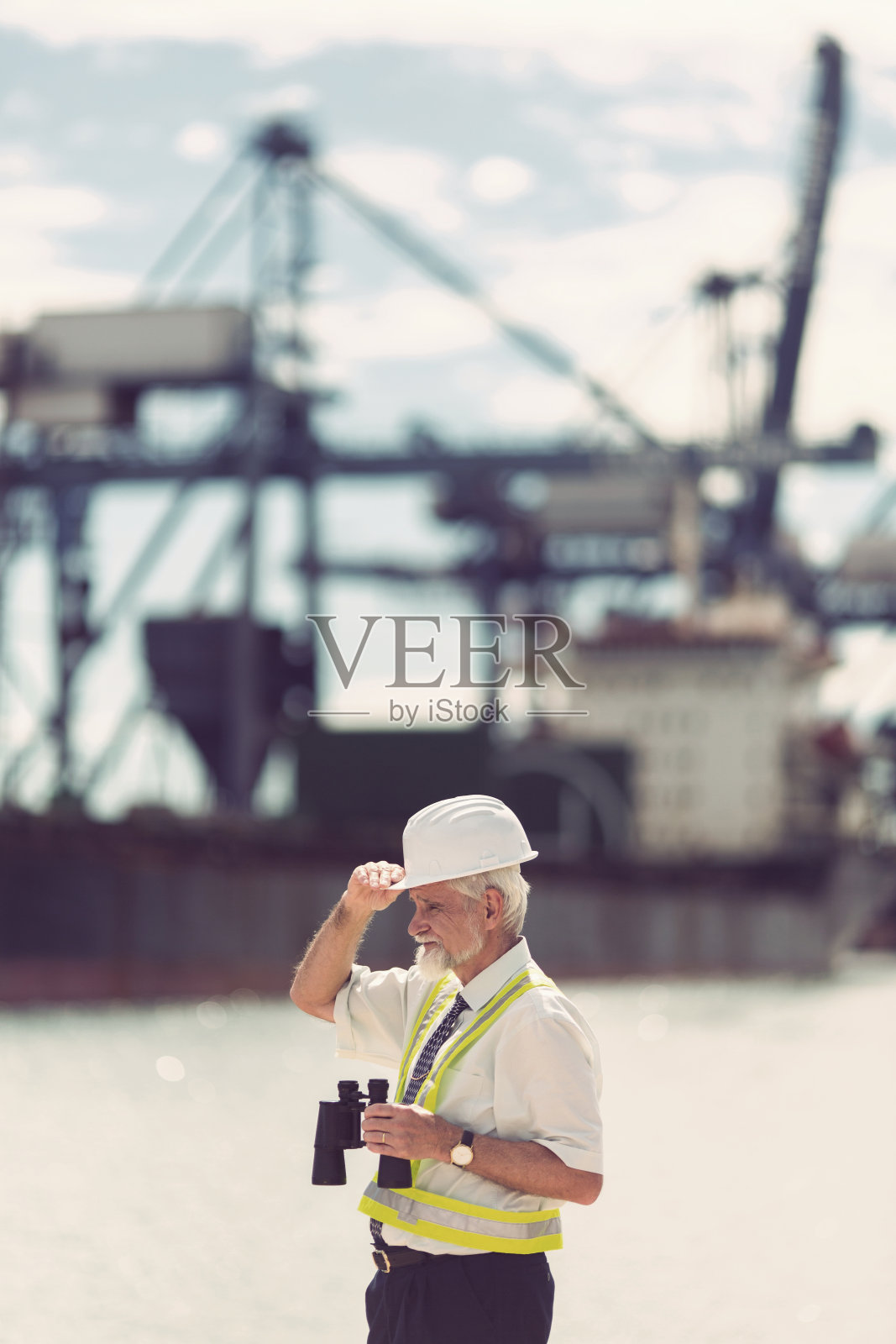 高级商人用双筒望远镜在海港视察工作照片摄影图片