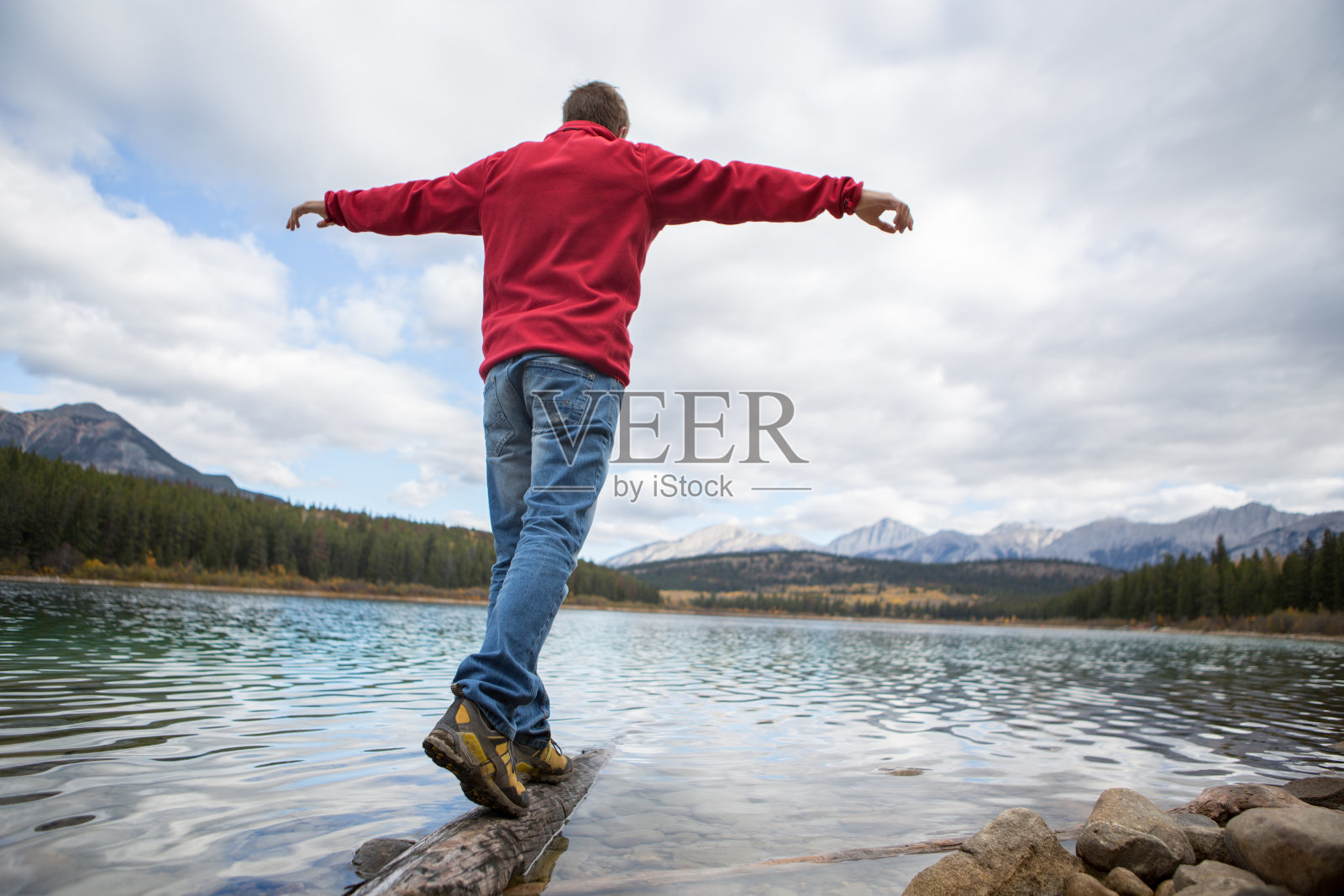 男子走在湖中的树干上照片摄影图片