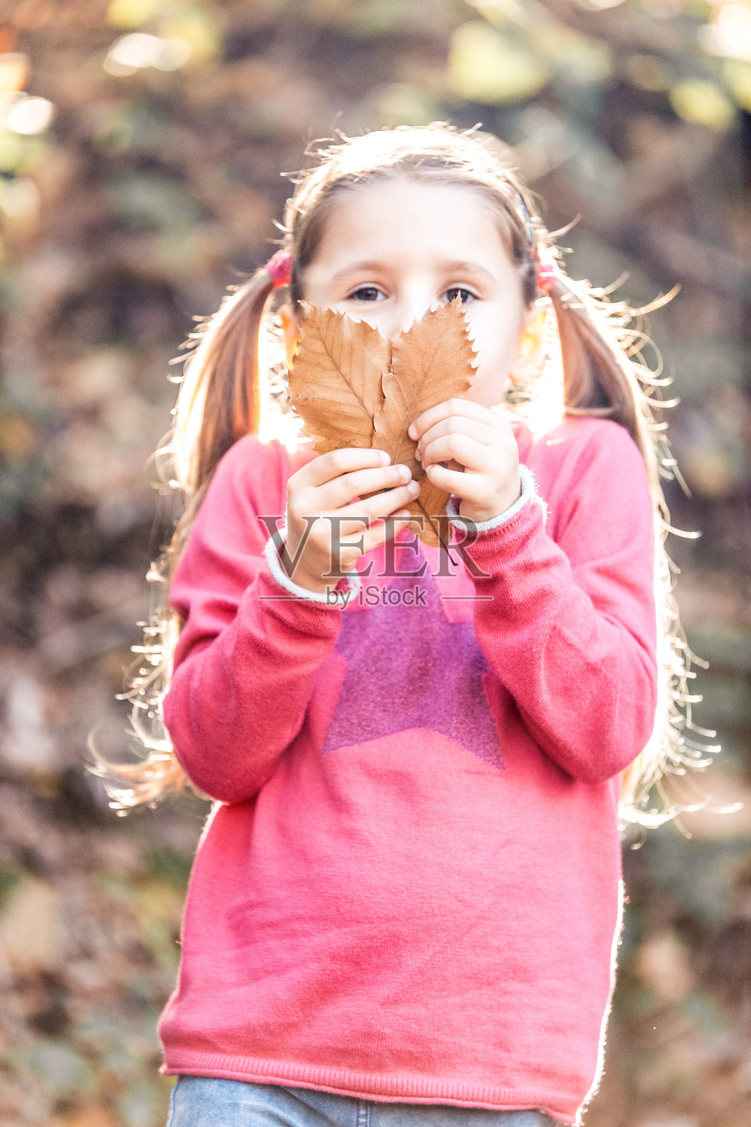 快乐的小女孩与秋叶嬉戏的肖像照片摄影图片