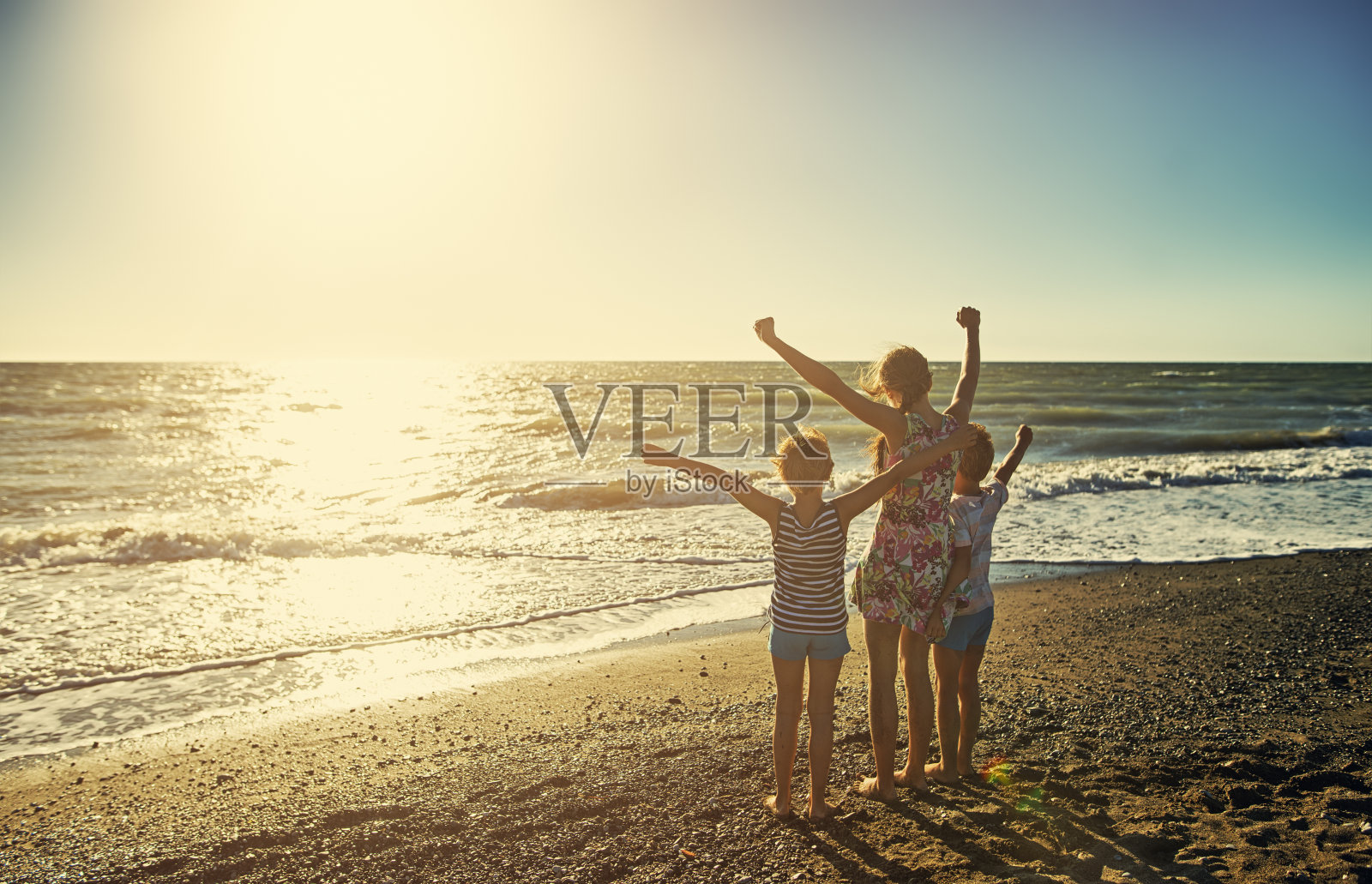 孩子们享受托斯卡纳海滩上的日落照片摄影图片