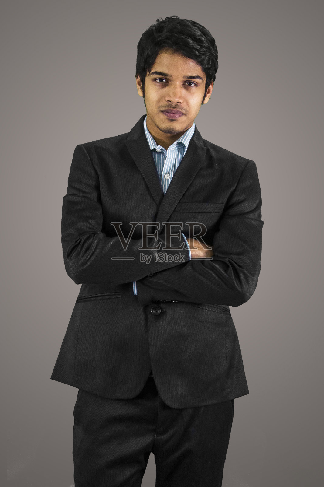 年轻的商人双臂交叉。照片摄影图片