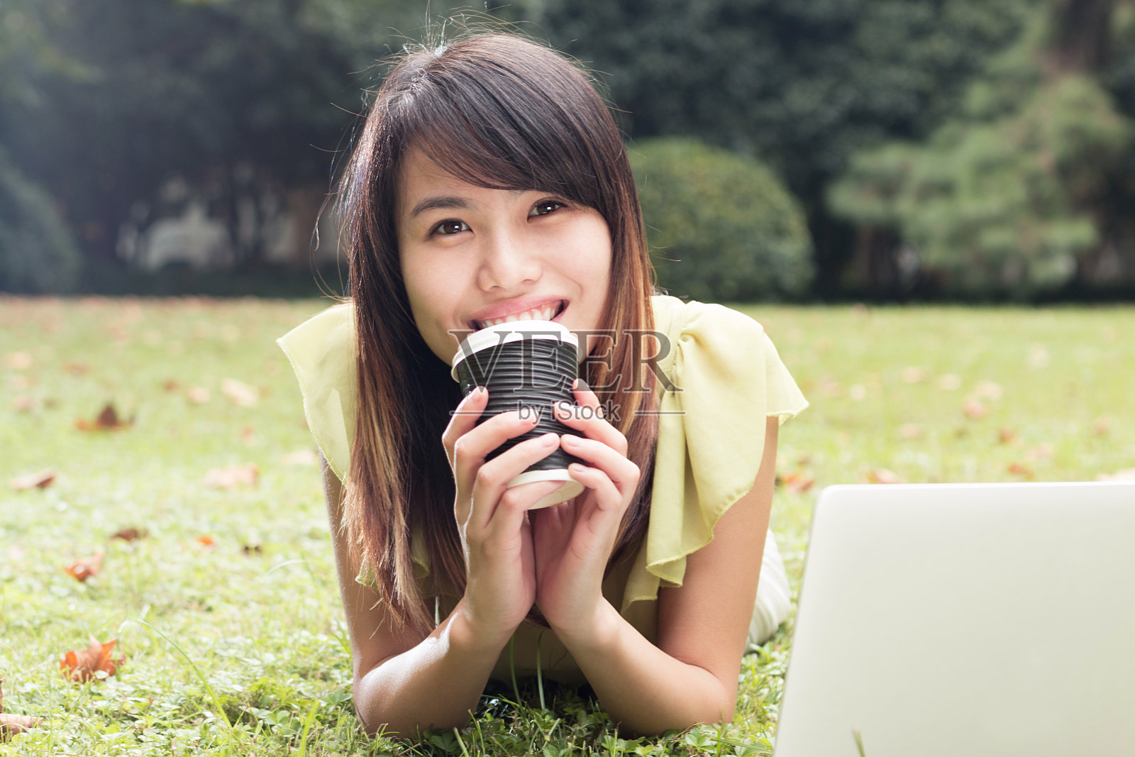 亚洲女学生与笔记本电脑放松在草地上照片摄影图片