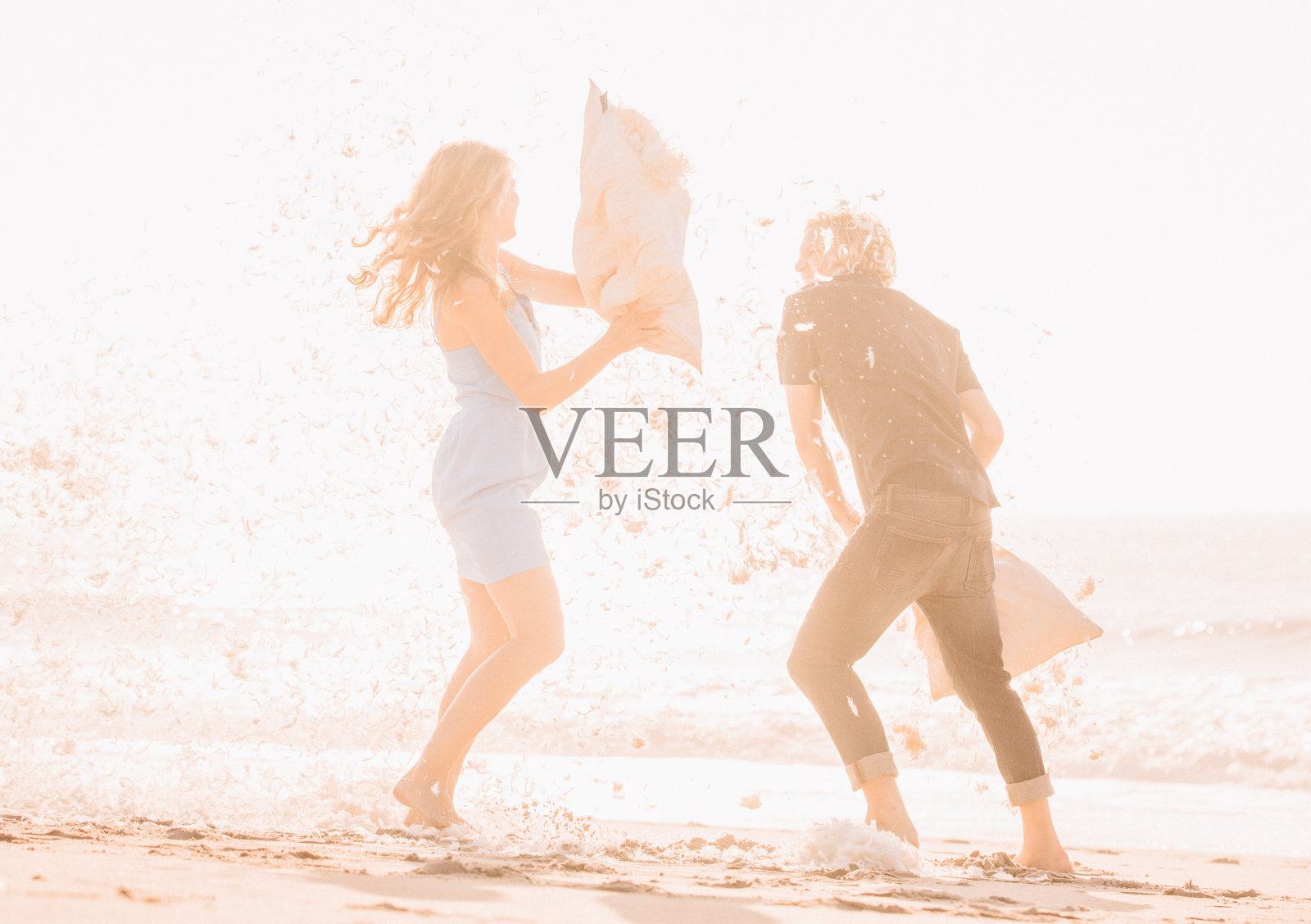 潮人情侣在沙滩上玩枕头大战照片摄影图片