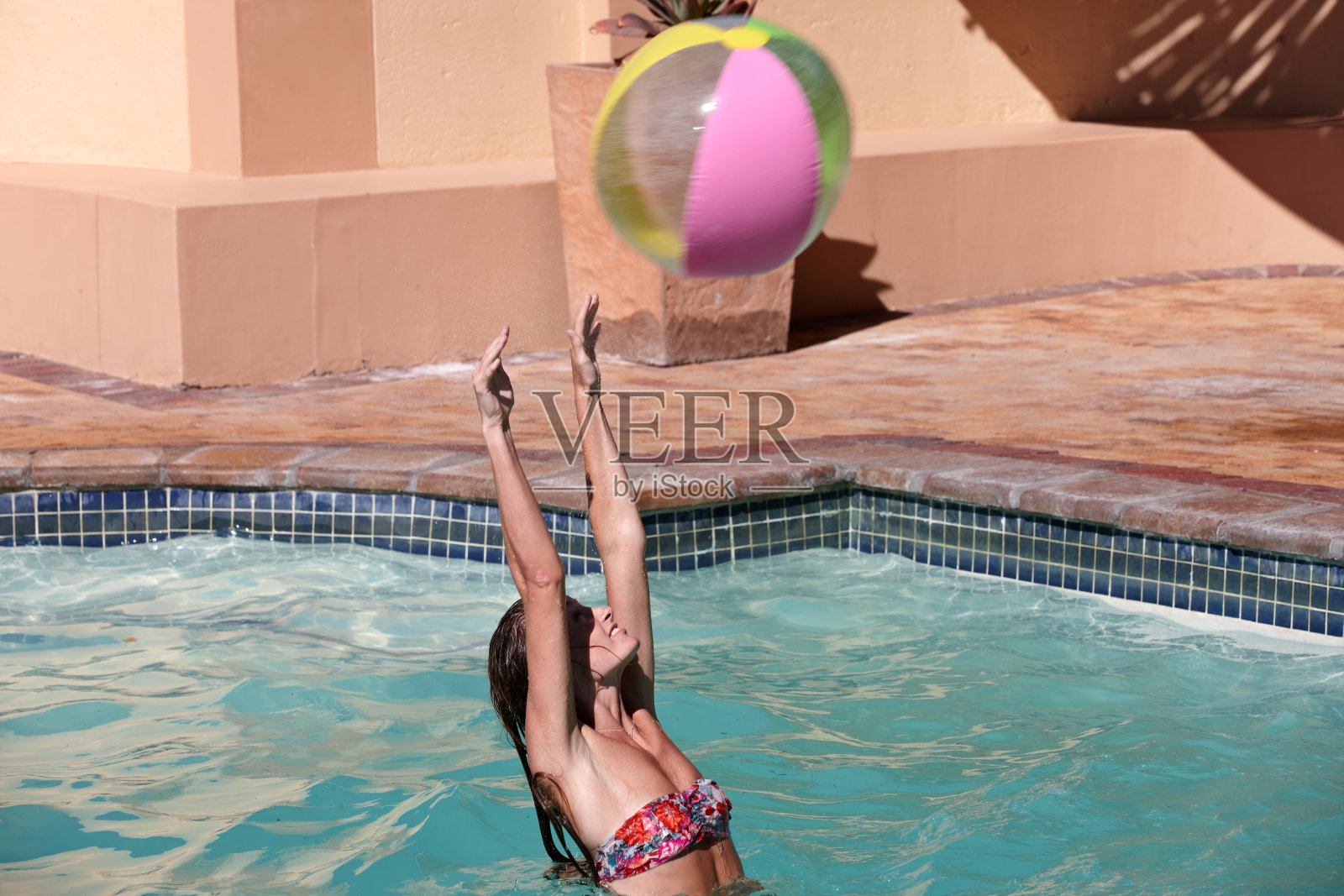 年轻的女性成年人在游泳池里玩沙滩球照片摄影图片