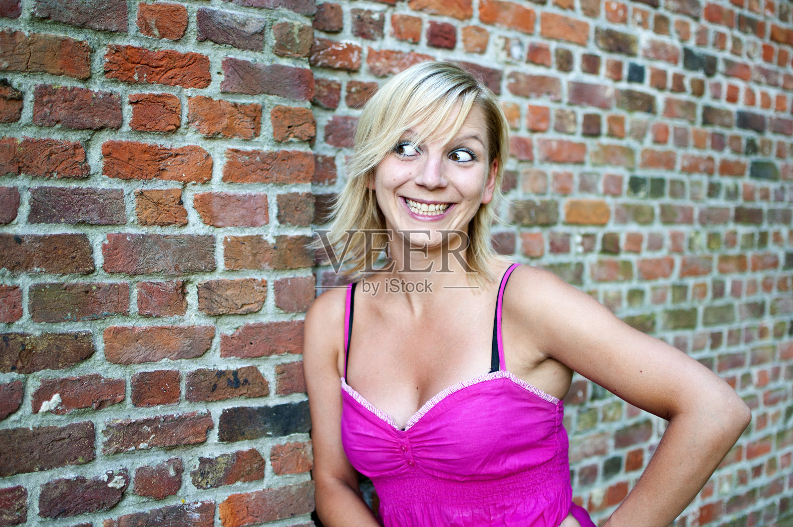 年轻女子站在砖墙上照片摄影图片