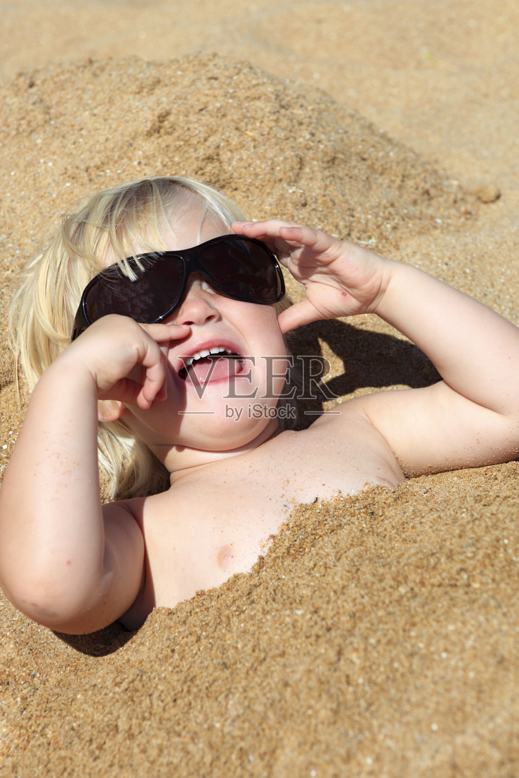 海滩上戴着太阳镜的金发男孩照片摄影图片