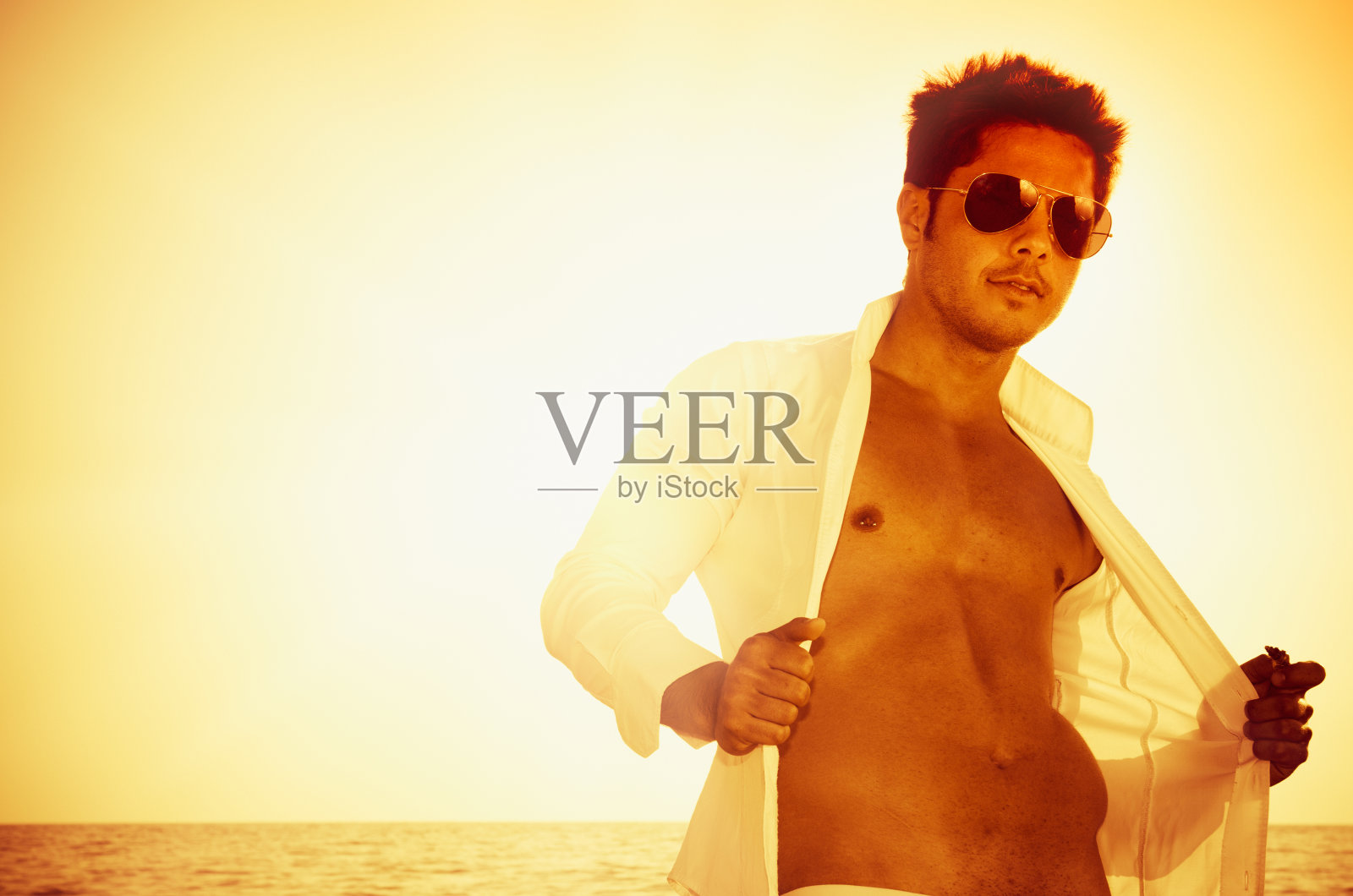 英俊的肌肉晒黑的家伙摆姿势在黄昏照片摄影图片