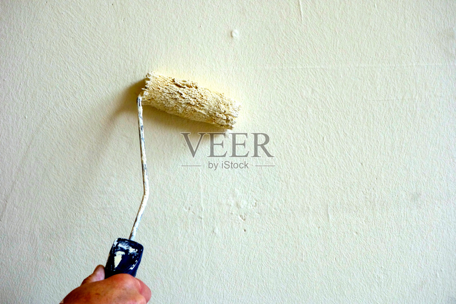 油漆工在用滚筒刷墙照片摄影图片