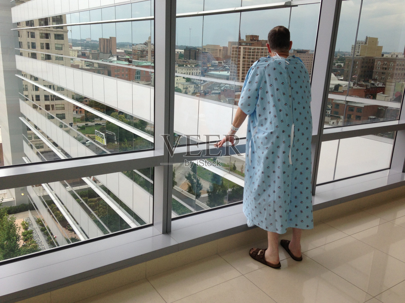 老年男病人向窗外看城市风景照片摄影图片