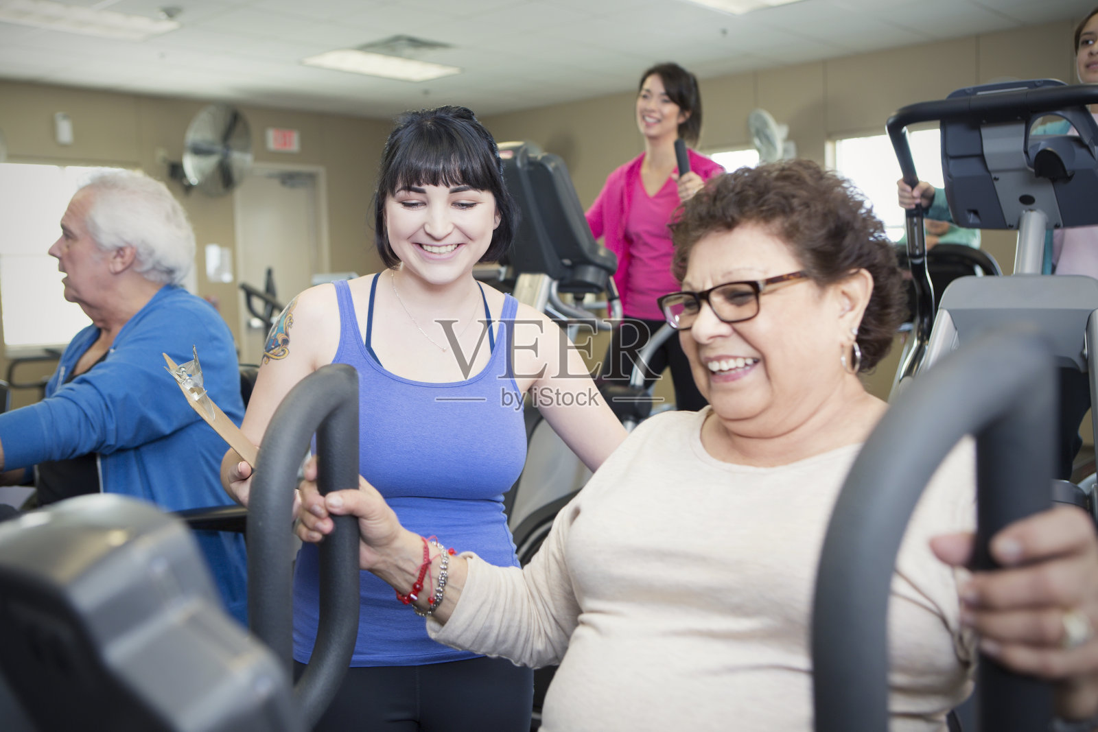 西班牙裔老年妇女在健身房使用机器照片摄影图片