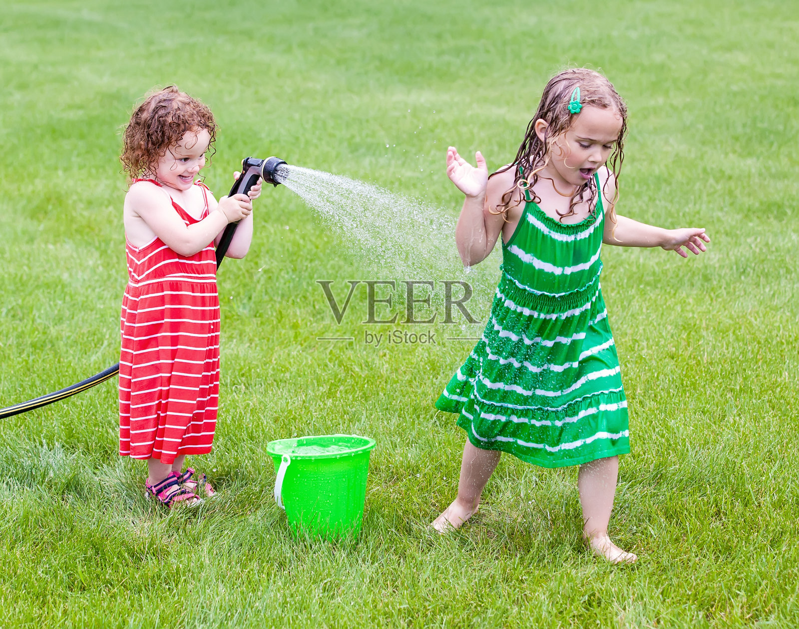 女孩们玩花园软管照片摄影图片