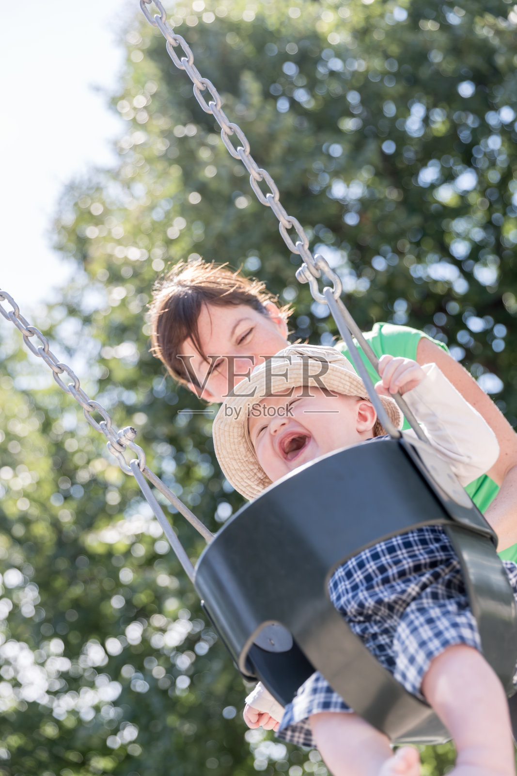 快乐的小男孩坐在操场上和妈妈在户外荡秋千照片摄影图片