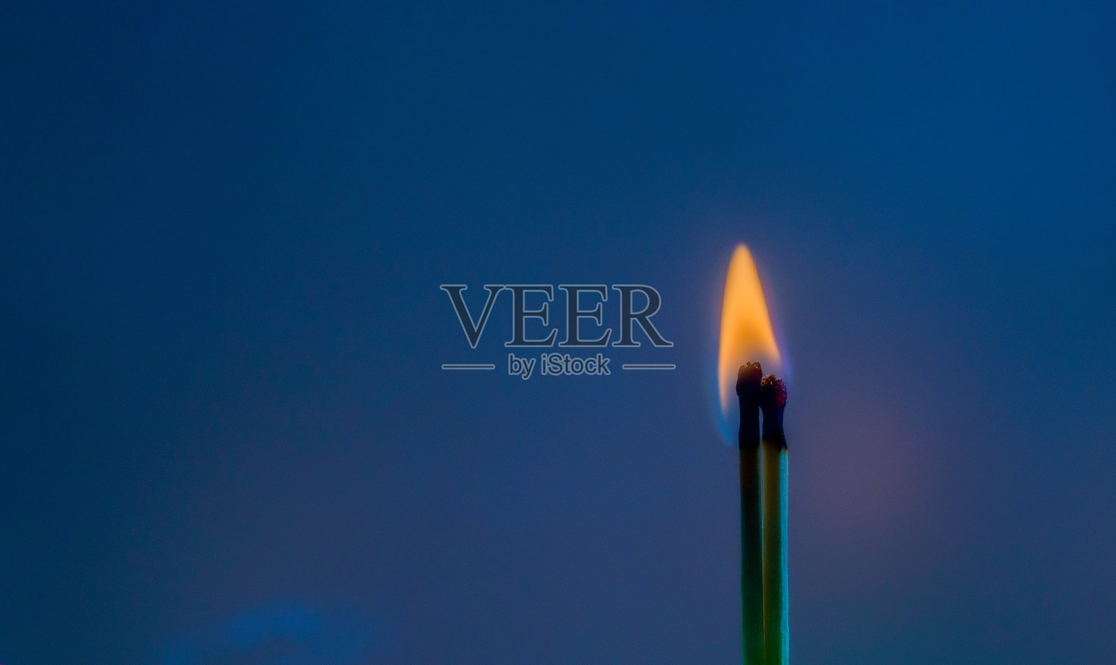 两根燃烧的火柴映衬着黑暗的背景照片摄影图片