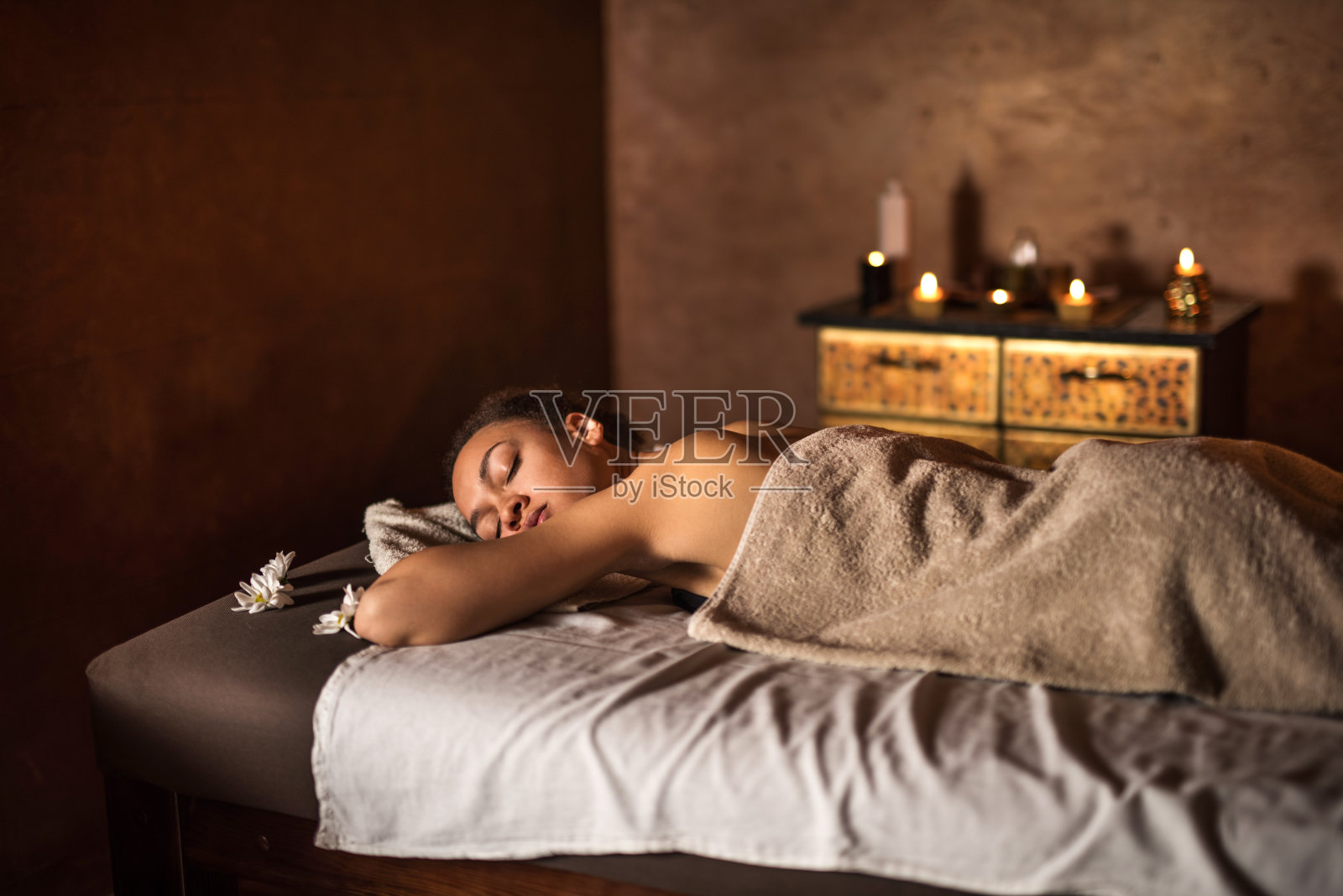 一位非裔美国妇女闭着眼睛在水疗中心休息。照片摄影图片