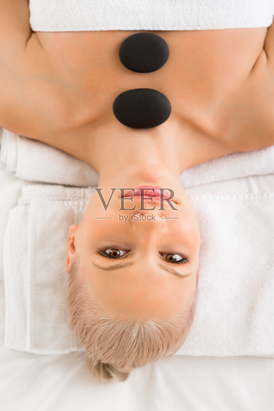 上图是一个女人正在进行热结石治疗照片摄影图片