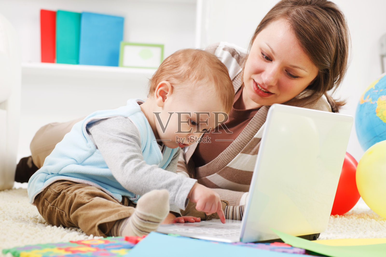 小男孩和他妈妈在电脑上工作。照片摄影图片