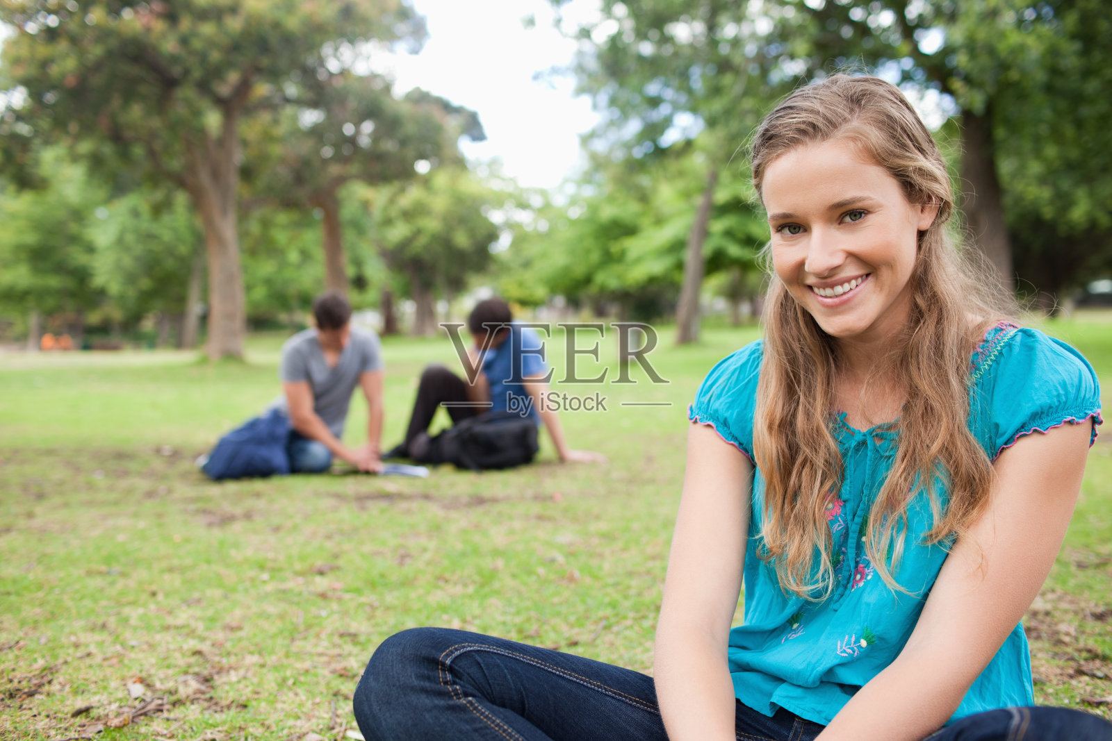 一个快乐的学生坐在草地上的特写照片摄影图片