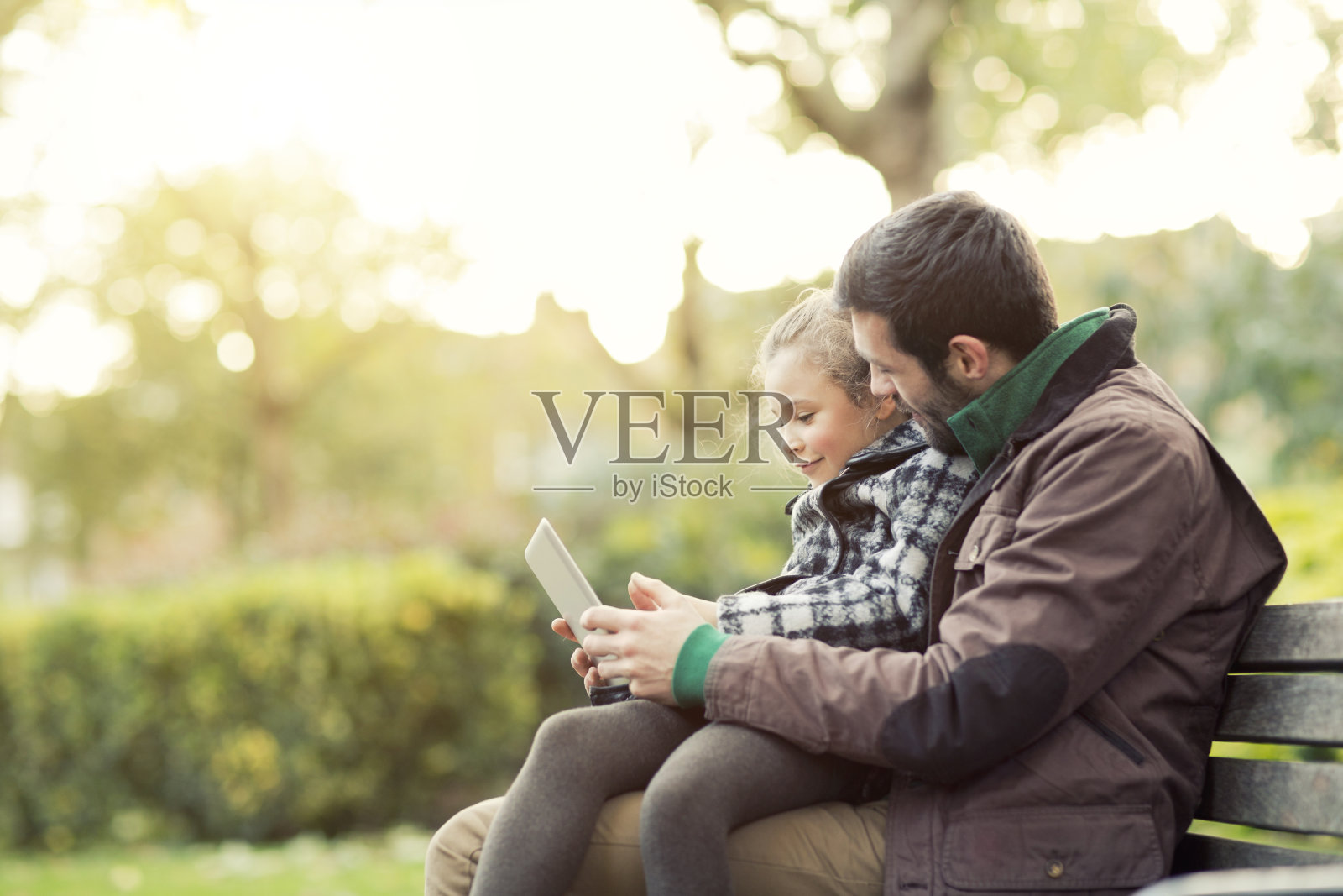 爸爸和女儿在公园里看平板电脑照片摄影图片