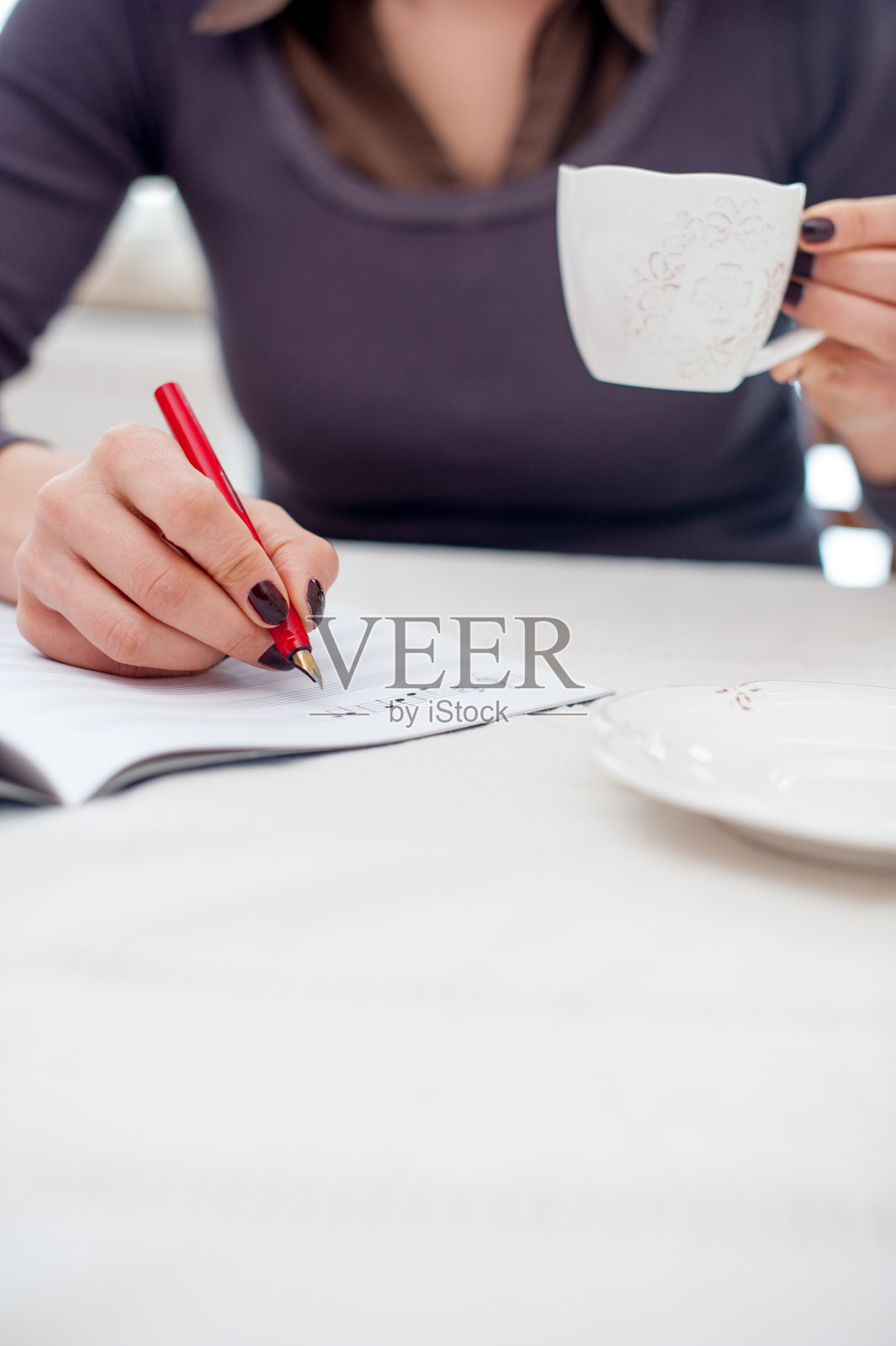 年轻女子在写音符的时候喝咖啡休息-双手合十照片摄影图片