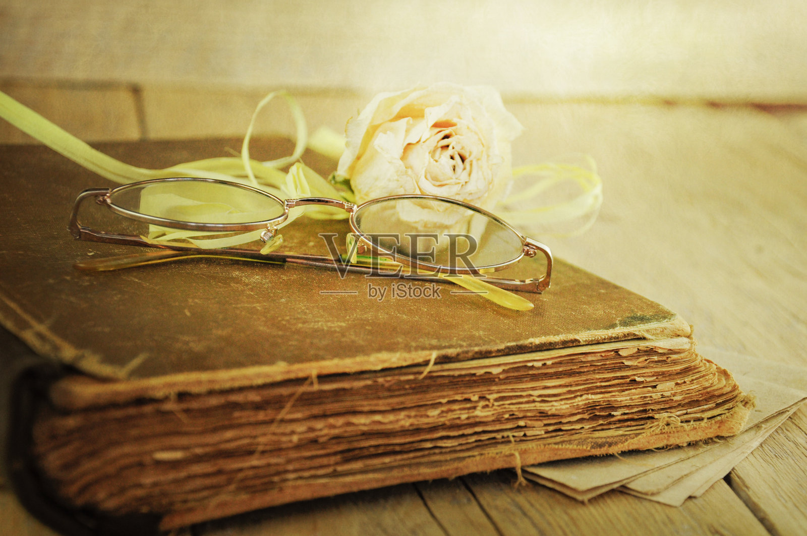 干枯的玫瑰和玻璃杯放在一本旧书上照片摄影图片