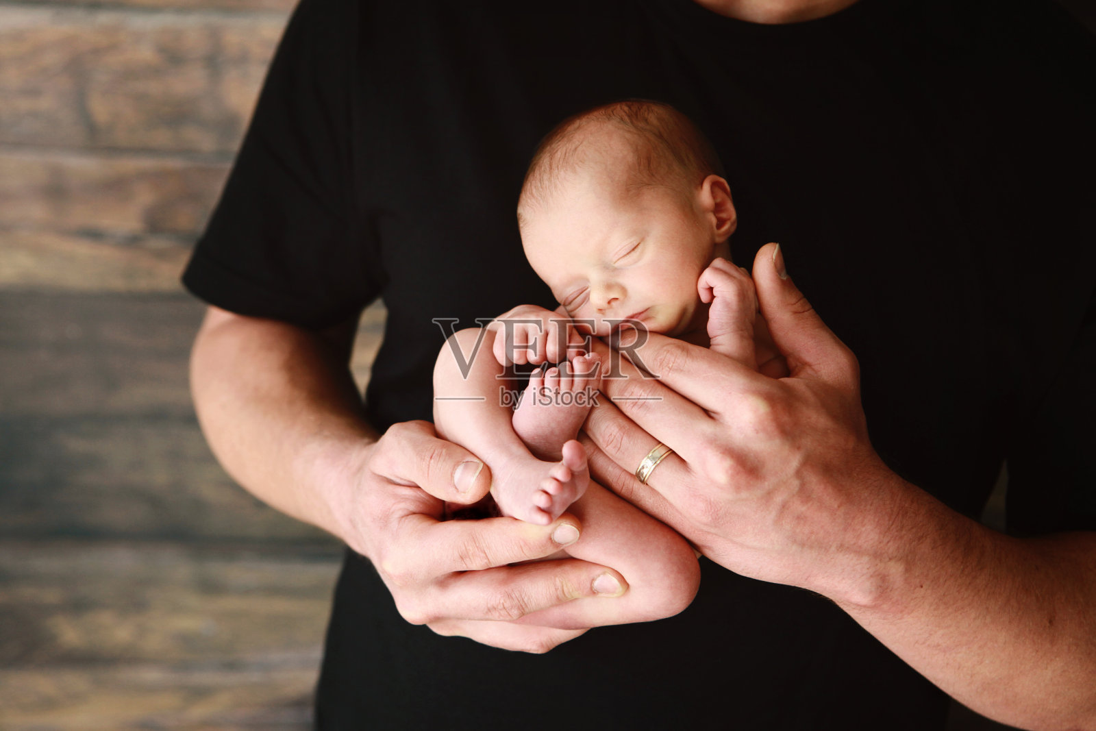 刚出生的婴儿睡在爸爸的怀里照片摄影图片