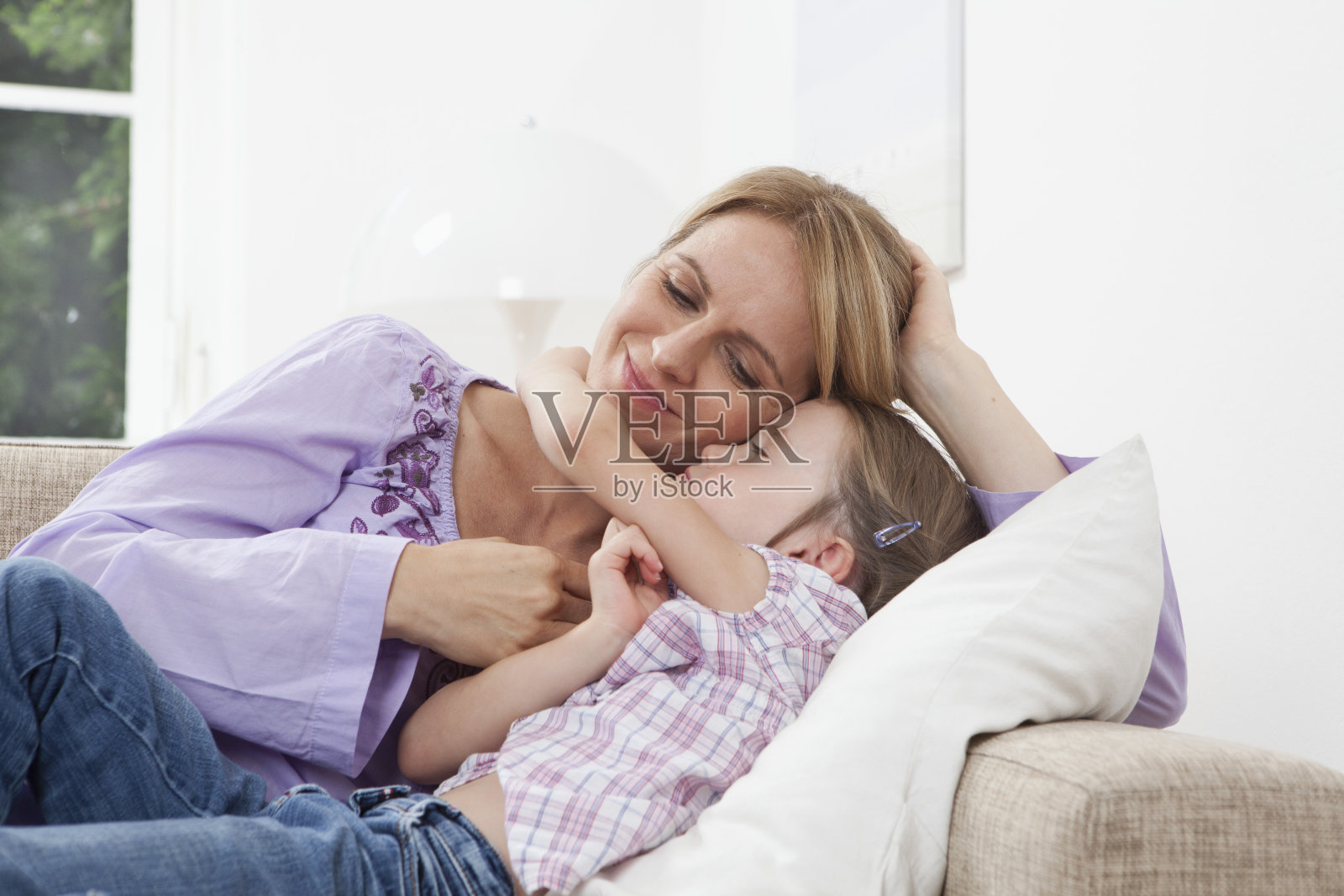 德国,慕尼黑,母亲和女儿(4-5岁)躺在沙发上照片摄影图片